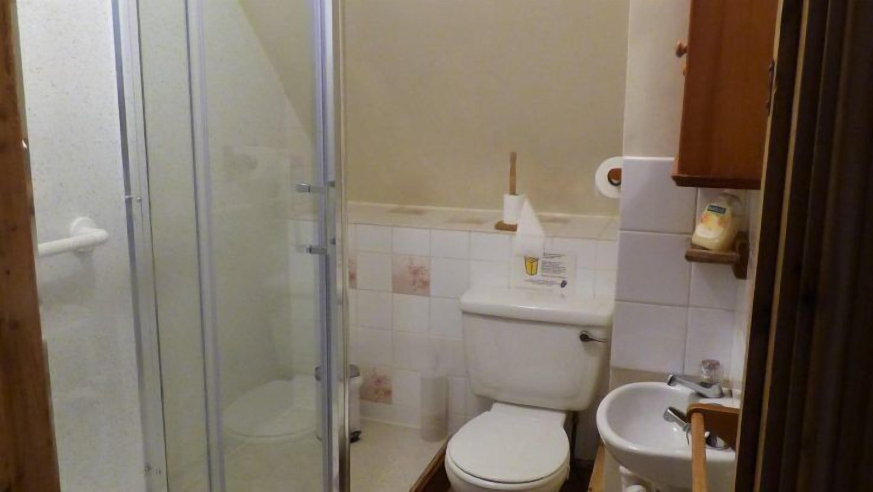 Un baño pequeño con inodoro, lavamanos y cabina de ducha.