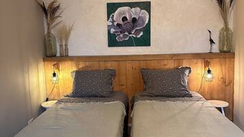 Una cama doble con cabecera de madera, dos mesitas de noche y un cuadro colgado en la pared con una flor.