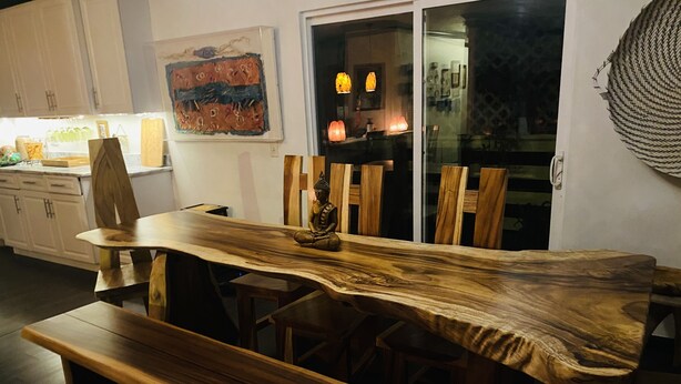 Une table à manger au design original, en bois, entourée de chaises et d’un banc.