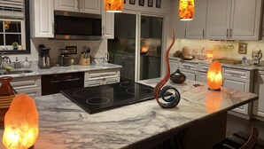 Une cuisine moderne avec des meubles blancs, une cuisinière noire et deux luminaires suspendus originaux.