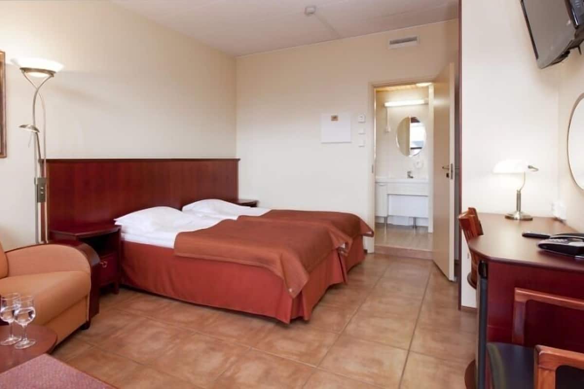 Een hotelkamer met een bed, bureau, stoel, bank en televisie.