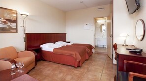 Una habitación de hotel con cama, escritorio, silla, sofá y televisor.