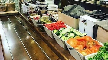 Noutopöydässä on tarjolla monenlaista ruokaa, kuten viipaloituja kurkkuja, tomaatteja ja etikkaliemessä säilöttyjä kasviksia.