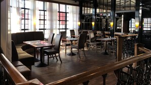 A restaurant interior with high ceilings, large windows, and a mix of seating arrangements including tables and booths. - Kauhajoen Krouvi (Kauhajoki)
