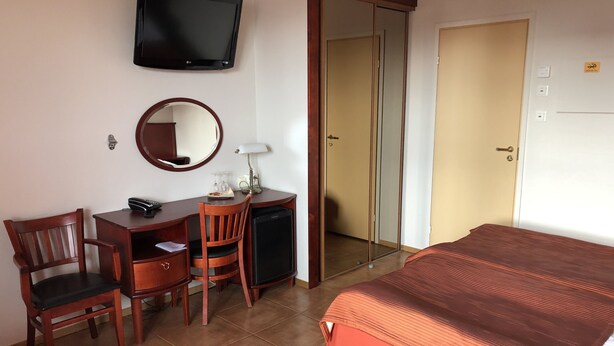 A hotel room with a bed, a desk with a chair, a television, a mirror, and a wardrobe. - Kauhajoen Krouvi (Kauhajoki)