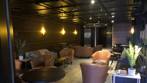 A modern lounge area with leather sofas, round tables, and potted plants. - Kauhajoen Krouvi (Kauhajoki)