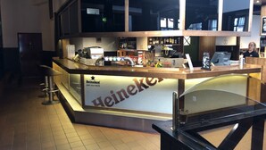 A bar area with a Heineken sign, a cash register, and various bottles and glasses. - Kauhajoen Krouvi (Kauhajoki)