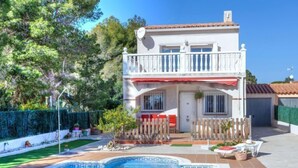 A two-story house with a swimming pool, a fenced patio, and a garden.