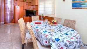 A dining area with a round table, wicker chairs, and a fruit bowl.