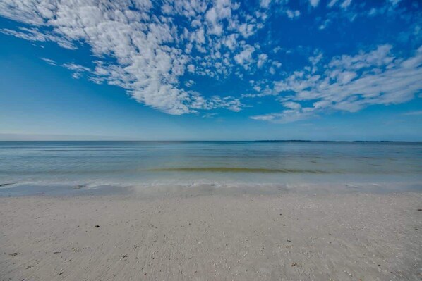 En strand med klart himmel og roligt vand.