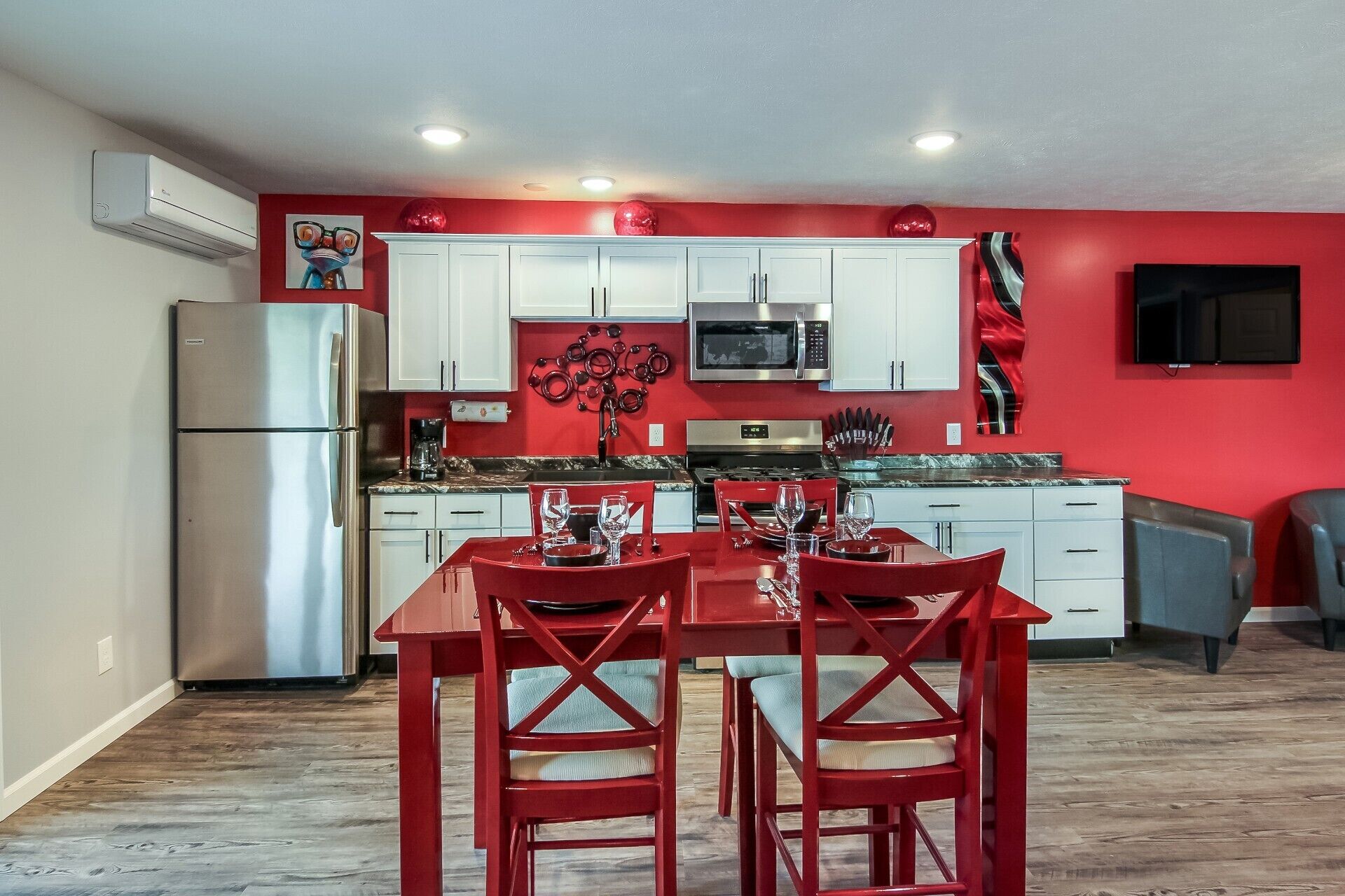 A compact kitchen with white cabinets, a stainless steel refrigerator, a microwave, and a stove.