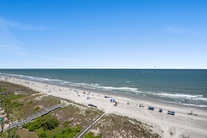 Une plage avec une longue promenade en bois, une étendue de sable et l’océan.