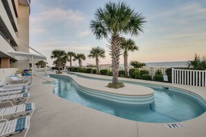 Un espace piscine avec des chaises longues et des palmiers.