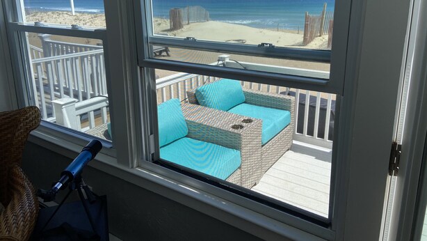 Een balkon met rieten meubilair en een telescoop.