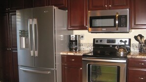 A kitchen with a stainless steel refrigerator, a microwave, and an oven. - Stunning elevated mountain and lake views at Palm Valley Country Club! (Palm Desert)