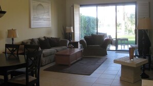 A living room with a sofa, armchair, coffee table, and TV. - Stunning elevated mountain and lake views at Palm Valley Country Club! (Palm Desert)