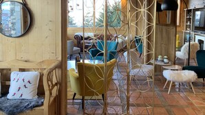 A cozy living room with wooden walls, a large window, and a mix of modern and classic furniture. - Alp'Azur Hotel (Huez)
