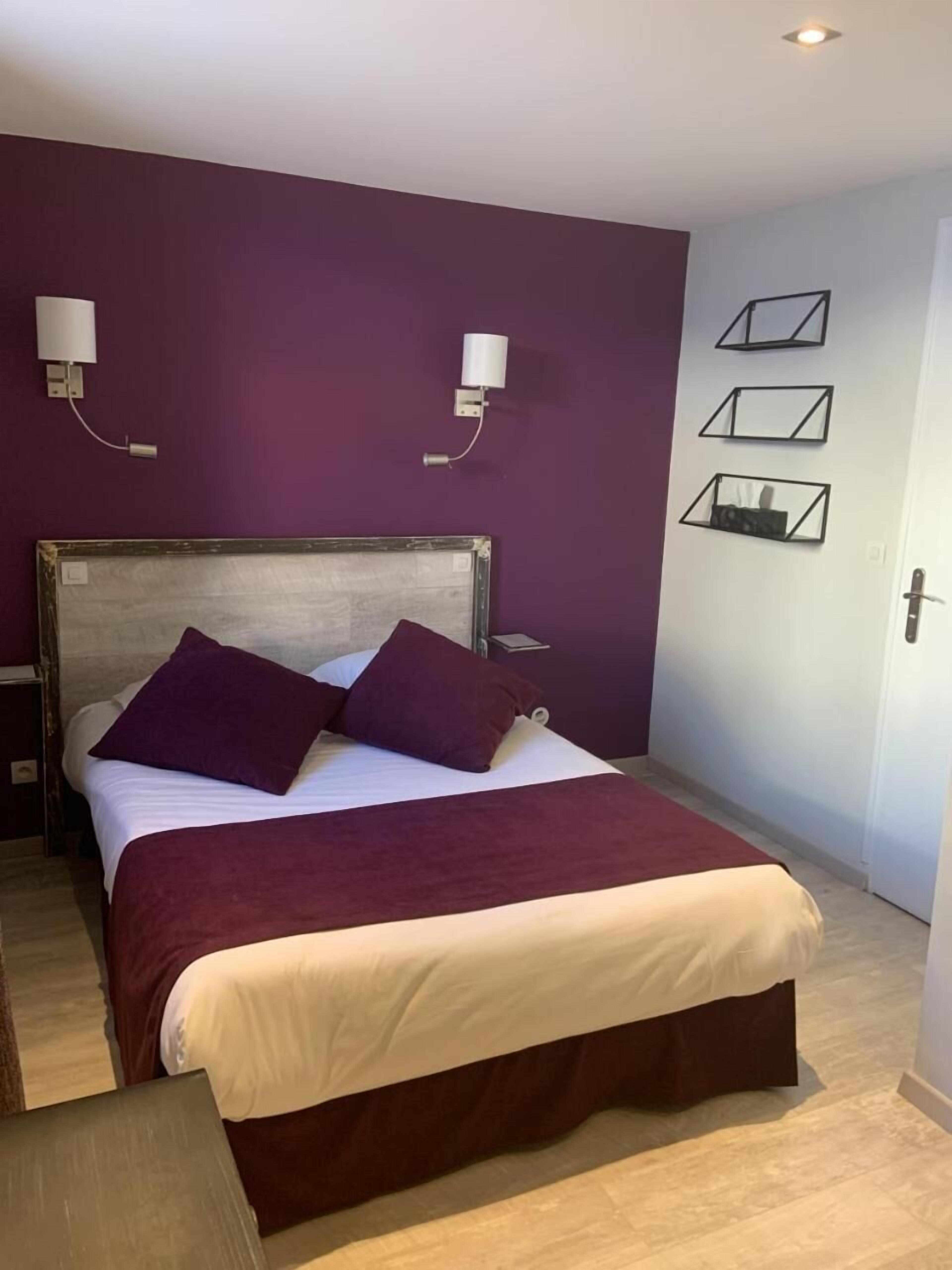 Een slaapkamer met een bed, paarse muren en een deur.