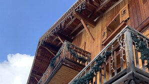 A wooden chalet with a stone facade, balconies with railings, and a wooden staircase. - Alp'Azur Hotel (Huez)