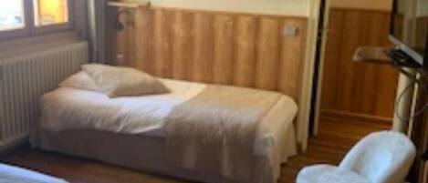 Quarto com duas camas, uma cadeira e uma televisão.