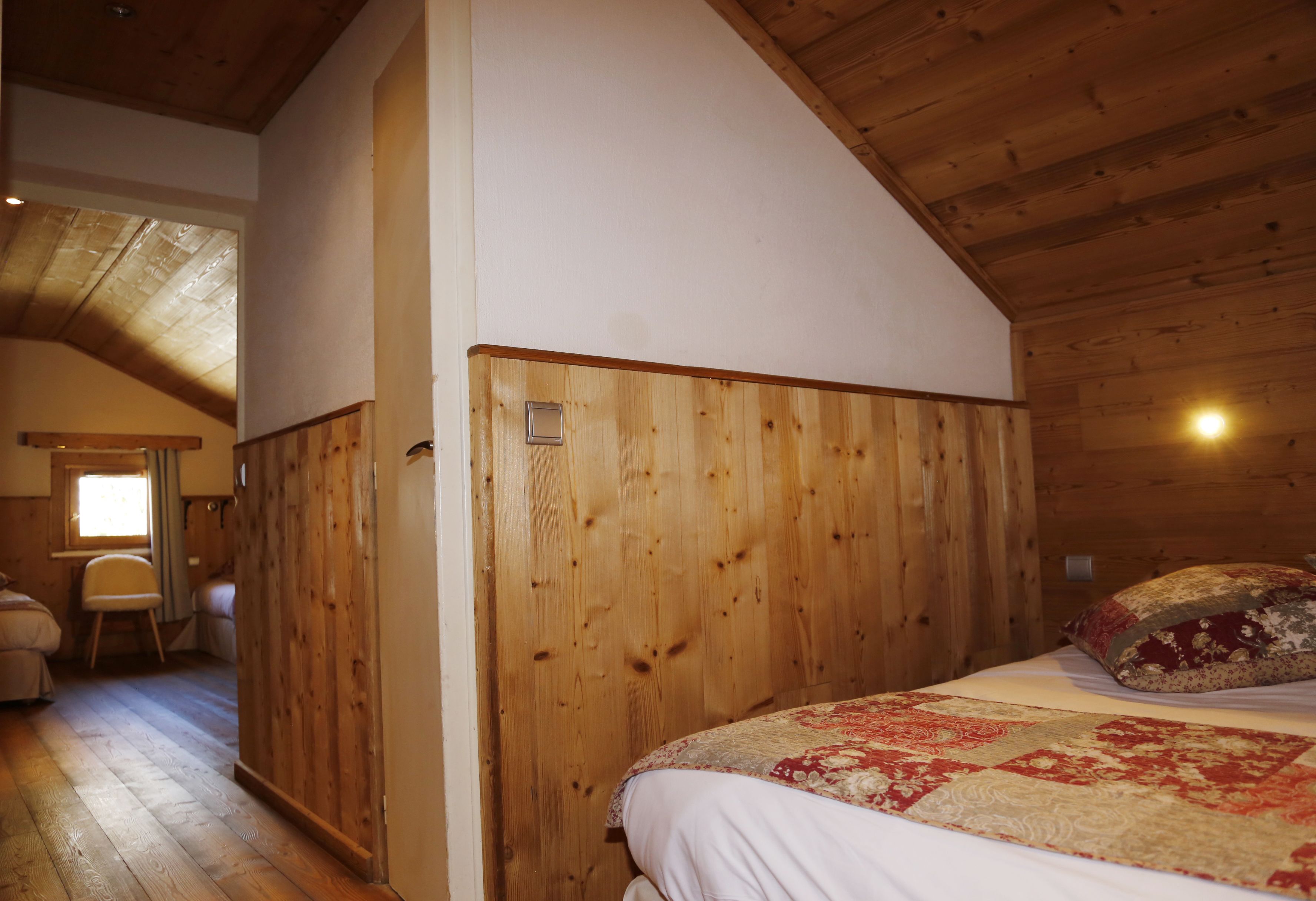 Dormitorio con paneles de madera, una cama, una mesita de noche y un ventanal.