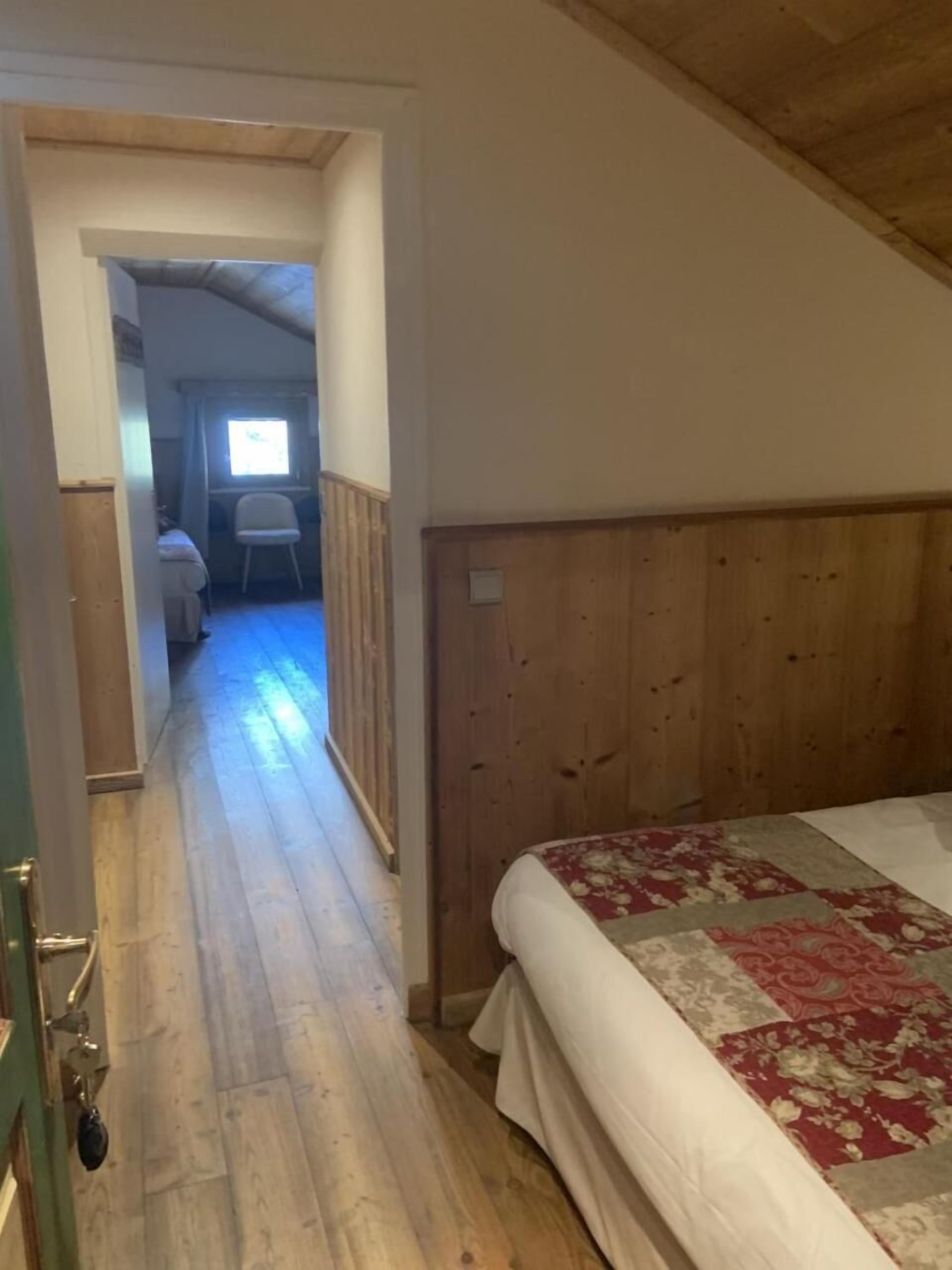 Un dormitorio con cabecera de madera, cama con colcha floral y ventana con cortinas.