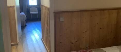 Un dormitorio con cabecera de madera, cama con colcha floral y ventana con cortinas.