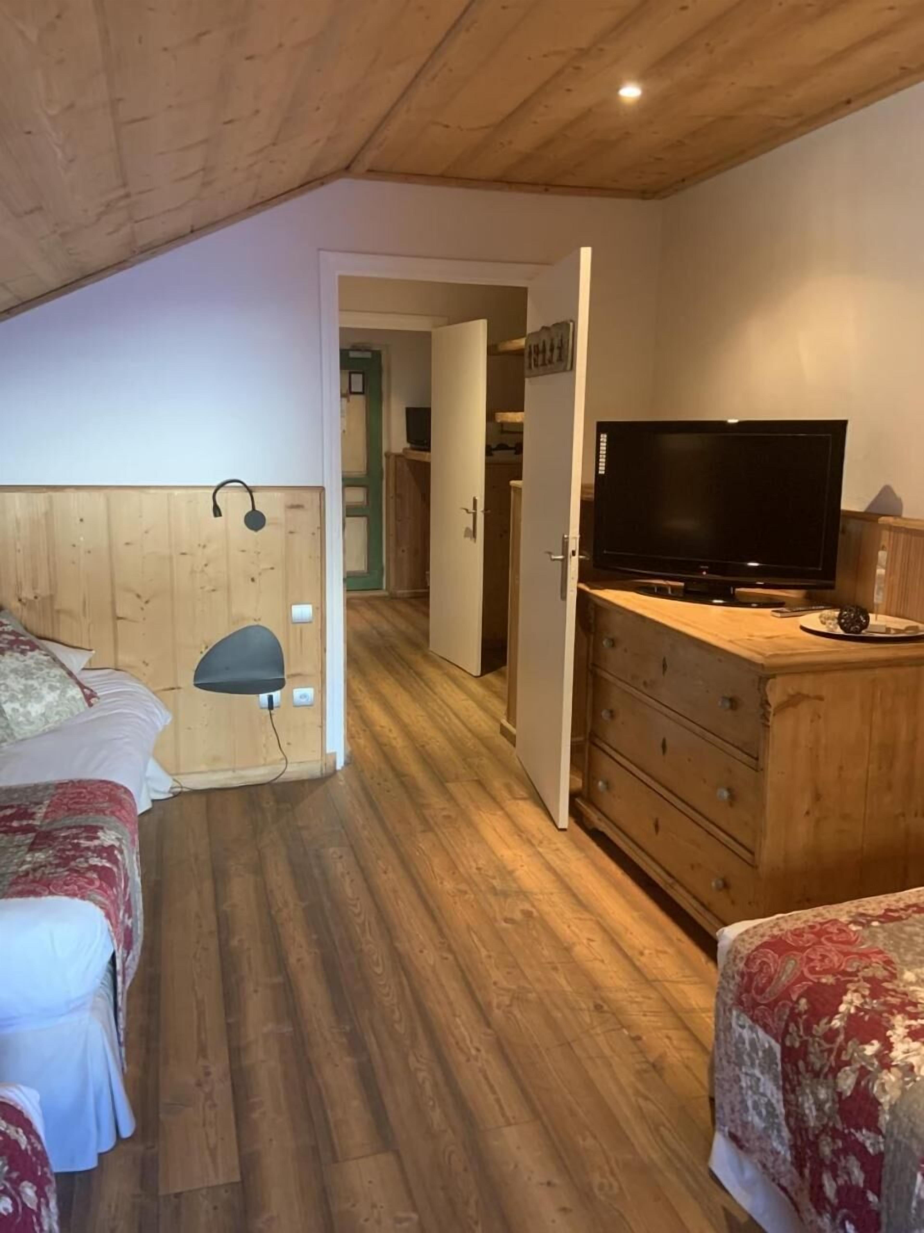A bedroom with two beds, a TV, and a wooden dresser.