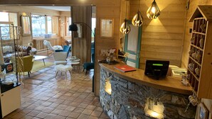 A wooden interior with a stone counter, blue chairs, and a white fluffy stool. - Alp'Azur Hotel (Huez)