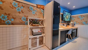 A modern kitchen with a refrigerator, a TV, and a small dining area. - Tirol Motel (Ulsan)