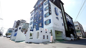 A multi-story building with a white facade and blue accents, featuring multiple windows and a prominent clock. - Tirol Motel (Ulsan)
