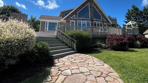 A modern two-story house with a stone pathway leading to the front door, surrounded by well-maintained lawns and bushes. - Luxury House in the Cavendish Area with Pool, Hot Tub and Air Conditioning (Stanley Bridge)