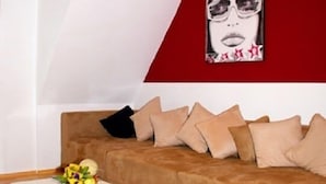 Un salon avec un canapé marron, une table basse blanche et un mur d’accent rouge orné d’une affiche.