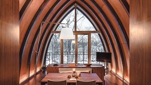 A dining area with a wooden table and chairs, a lamp, and a view through large windows. - Andaru Collection Niseko (Kutchan)