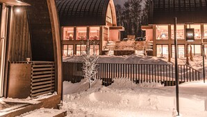 A snow-covered outdoor area with wooden buildings, steps leading to a door, and a snow-covered tree. - Andaru Collection Niseko (Kutchan)