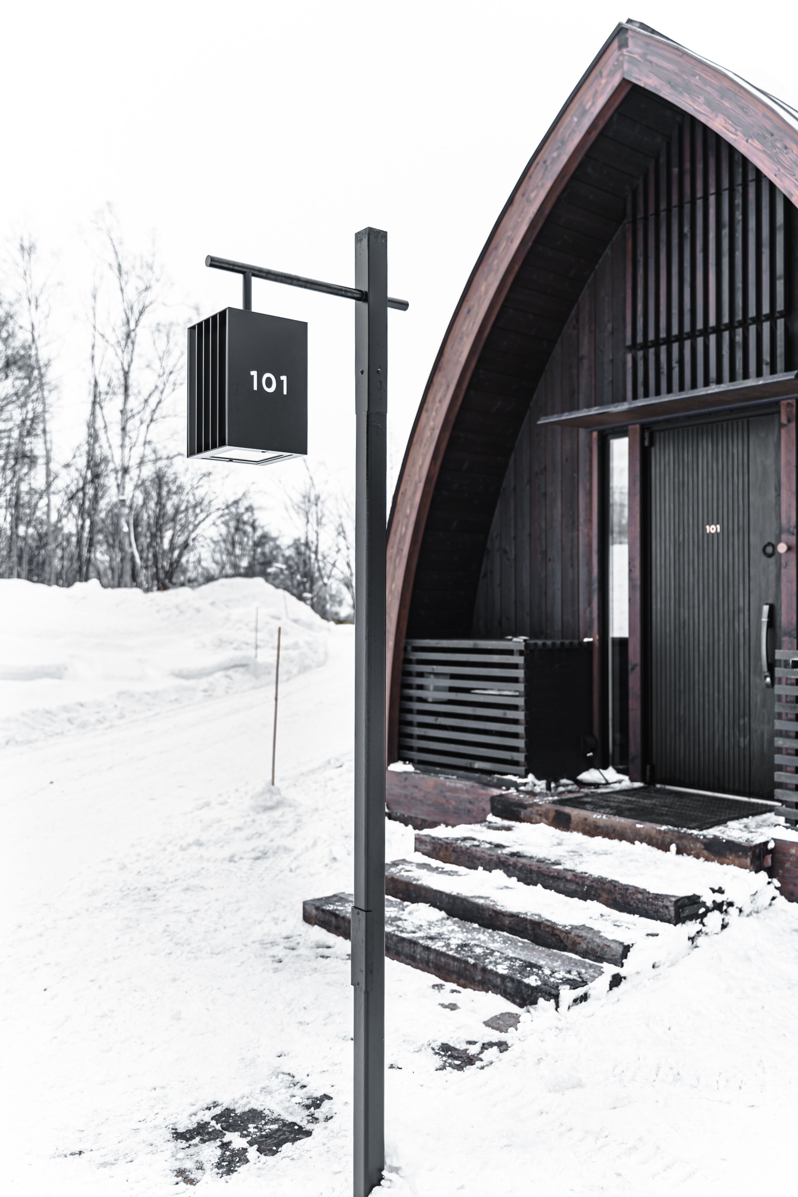 A modern building with a unique arched entrance and a sign indicating room number 101.