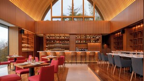 A modern restaurant with wooden paneling, large windows, and a variety of seating arrangements. - Andaru Collection Niseko (Kutchan)