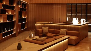 A modern interior with a wooden reception desk, a sofa area, and built-in shelves. - Andaru Collection Niseko (Kutchan)