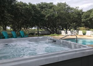 A hot tub with a pool in the background, surrounded by trees and lounge chairs. - Thanks Dad: 6 Bedrooms, Large Private Pool, Hot Tub (Corolla)