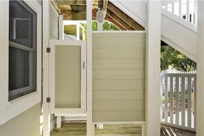 Una terrassa de fusta amb una porta blanca i una finestra.