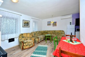 A living room with a sofa, a dining table with chairs, a small green table, and a red tablecloth. - Bacvice Beach Apartment (Split)