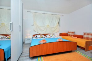 A bedroom with two beds, a wardrobe, a bedside table, and a window with curtains. - Bacvice Beach Apartment (Split)