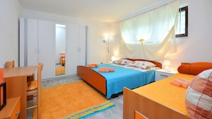 A bedroom with a bed, a desk, and a chair. There is a window with curtains and a lamp on the bedside table. - Bacvice Beach Apartment (Split)
