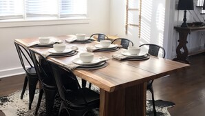 A dining area with a wooden table set for six, black chairs, and a cowhide rug. - Walk to Journeyman Renovated Spacious Victorian House, Beautiful Vintage Details (Three Oaks)