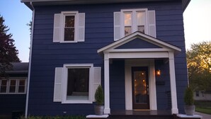 A two-story house with a dark blue exterior, white trim, and a front porch with steps leading to the entrance. - Walk to Journeyman Renovated Spacious Victorian House, Beautiful Vintage Details (Three Oaks)