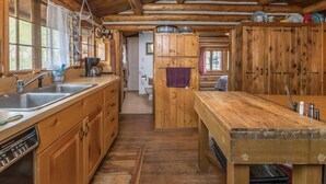 Ein rustikales Holzhaus-Interieur mit Küchenzeile, die Holzschränke, ein Spülbecken und einen Esstisch zeigt.