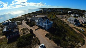 Vista aérea de una zona residencial costera con casas, un camino de tierra y una playa.