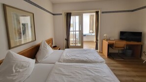 Hotelkamer met twee bedden, een bureau met een televisie en uitzicht op het balkon.