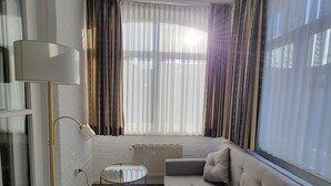 Een moderne woonkamer met een witte bank, een vloerlamp en een radiator.