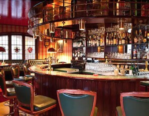 Un bar doté d’un comptoir incurvé, de plusieurs espaces pour s’asseoir et d’une variété de bouteilles et de verres exposés sur des étagères.